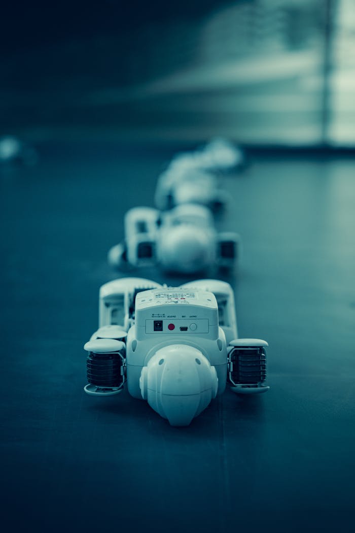Home Vertical shot of white robots aligned on a dark surface, emphasizing technology.